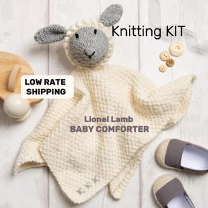 May include: Knitting kit for a Lionel Lamb baby comforter. The kit includes instructions and yarn to knit a white baby blanket with a gray and white lamb head attached.