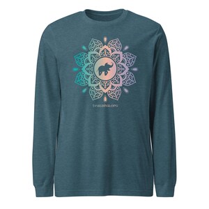 May include: Teal long-sleeve shirt with a mandala design featuring an elephant silhouette in the center. The mandala has teal, pink, and purple accents. The text "tealdiva.org" is printed below the mandala.