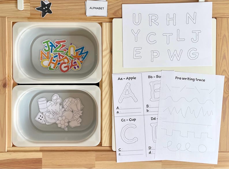 May include: A set of alphabet learning materials for children. The set includes a tray with magnetic letters, a sheet with uppercase letters to trace, and a sheet with lowercase letters to trace. The set also includes a sheet with pre-writing tracing exercises.
