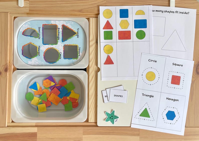 May include: A set of colorful foam shapes in a white container, along with a worksheet with various shapes and the text "How many shapes fit inside?"  The worksheet also includes the words "Circle", "Square", "Triangle", and "Hexagon".