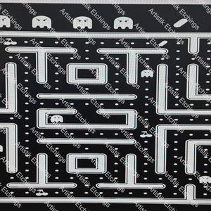 May include: A black and white Pac-Man themed design featuring the game's maze, Pac-Man, ghosts, and other game elements. The word "PAC-MAN" is displayed vertically on the right side. The design is etched with the words "Artistik Etchings" around the edges.