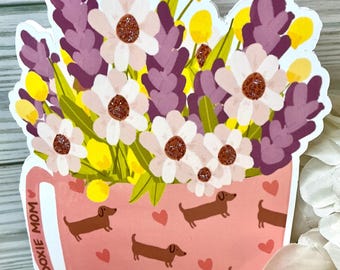 Könnte beinhalten: Eine rosa Tasse mit Dackel-Muster und dem Text "Doxie Mom" ist mit einem Strauß aus lila Lavendel, weißen Gänseblümchen und gelben Blumen gefüllt.