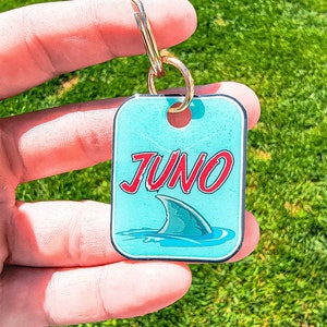 May include: A blue and red keychain with the word "JUNO" and a shark fin graphic.