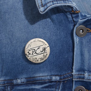 May include: A white button with black text that reads "Society for the Promotion of S.P.C.W. Fish Welfare".