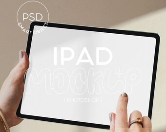 Op de afbeelding: Een witte iPad mockup met de tekst "IPAD MOCKUP | PHOTOSHOP |" op het scherm. Een hand houdt de iPad vast en een vinger wijst naar het scherm.