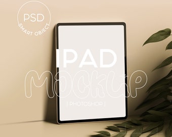 Op de afbeelding: Een digitale tablet-mockup met een leeg scherm, voorzien van de tekst PSD SMART OBJECT, IPAD MOCKUP, PHOTOSHOP en Digital ipad mockup by MUPY MOCKUP STUDIO, vergezeld door een groene tak met bladeren.