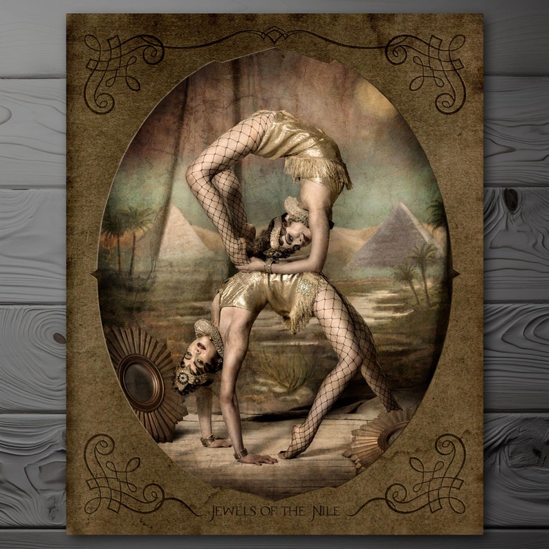 May include: Two women in vintage circus attire perform an acrobatic pose against a backdrop of a desert landscape with pyramids. The image is framed with a decorative border and the text "Jewels of the Nile" is at the bottom.