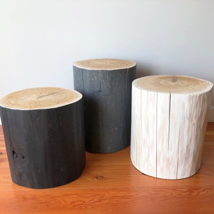 May include: Three wooden stumps, one painted black, one painted white, and one left natural, used as decorative side tables.
