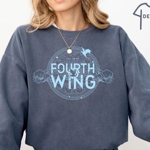 May include: A blue sweatshirt with a light blue graphic design featuring a circle with the text "Fly or Die" and "Fourth Wing" inside. The graphic also includes a stylized bird and clouds.