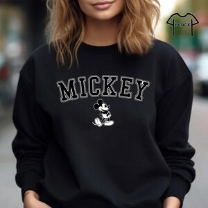 Puede incluir: Sudadera negra con un gr&aacute;fico de Mickey Mouse blanco y la palabra "MICKEY" en letras blancas.