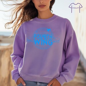 May include: A purple sweatshirt with a blue circle graphic that says "FOURTH WING" on it.