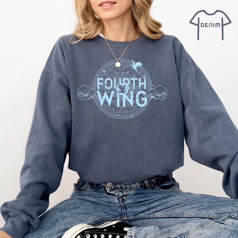 May include: A blue sweatshirt with a light blue graphic design featuring a circle with the text "Fly or Die" and "Fourth Wing" inside. The graphic also includes a stylized bird and clouds.