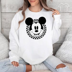 Peut inclure: Sweat-shirt blanc avec un cercle &agrave; carreaux noir et blanc autour d'une image noir et blanc du visage de Mickey Mouse.