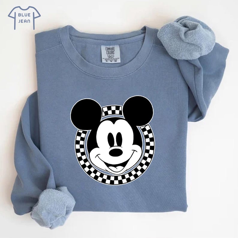 Peut inclure: Un sweat-shirt bleu avec un cercle &agrave; carreaux noirs et blancs autour d'un visage de Mickey Mouse blanc.