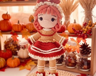 May include: A crocheted doll with peach-colored skin, curly coral-pink hair, and a large matching bow. The doll wears a tan long-sleeved top, a red skirt with white trim, and red shoes with white accents, standing on a round woven straw mat.