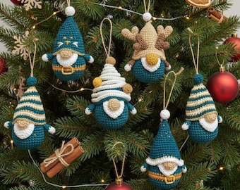 May include: A collection of six crocheted gnome ornaments hanging on a Christmas tree. The gnomes feature teal, white, and tan yarn, with pointed hats, round noses, and some with antlers or striped patterns, all suspended by thin twine loops.