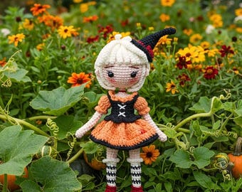 May include: A crocheted doll with white hair, wearing a black pointed hat with a red accent, a black bodice with white lacing, an orange skirt, and black and white striped stockings with red shoes, standing upright in a garden of flowers.