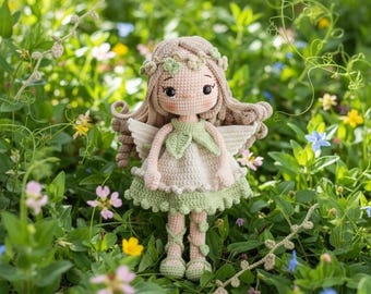 May include: A crocheted doll featuring light brown yarn hair adorned with a floral crown, wearing a pale green and cream dress with leaf accents, small white wings, and matching lace-up footwear, all crafted with detailed yarn stitching.