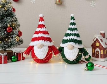 May include: Two handmade crochet gnomes with plush bodies and tall pointed hats. One gnome features a red and white striped hat with a red body, while the other has a green and white striped hat with a green body. Both have white beards.