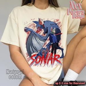 May include: Cream-colored t-shirt featuring a graphic of a bat-like creature with a person in a suit. The word "SONAR" is printed in red. The shirt also has the text "Natural color" and "up 2-3 size for Oversized".