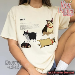 Puede incluir: Camiseta de color crema con ilustraciones de dibujos animados de un perro en varias poses. La camiseta incluye la palabra "BEEF" y texto que describe al perro. Las palabras "Natural color" y "up 2-3 size for Oversized" también están impresas en la camiseta.
