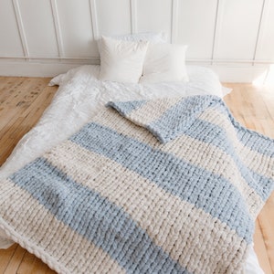 May include: A chunky knit throw blanket with alternating stripes of light blue and cream.