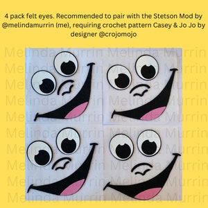 May include: Four felt eyes, each with a white circle and a black centre, are arranged in a grid pattern. Each eye is part of a felt face with a black smiling mouth and a pink tongue. The faces are on a white background.