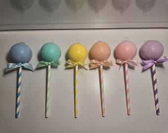 May include: Six colorful, glitter-covered sphere ornaments with ribbon bows, each on a striped stick. Colors include blue, teal, yellow, peach, pink, and purple. These decorative ornaments are perfect for Easter or other festive occasions.