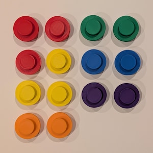 May include: A collection of twelve colorful, circular objects arranged in a grid. The objects are in shades of red, green, yellow, blue, purple, and orange. Each object has a raised, circular center.