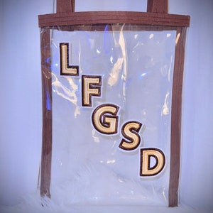 May include: Clear plastic tote bag with brown straps and the letters "LFGS" in gold embroidered patches.