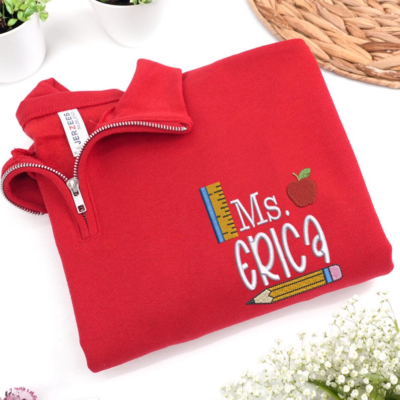 Custom embroidered red quarter-zip sweatshirt with “Ms. Erica” and cute apple, pencil, and ruler design — personalized teacher sweatshirt, perfect for back-to-school, thoughtful teacher appreciation gift, or cozy everyday classroom wear.
