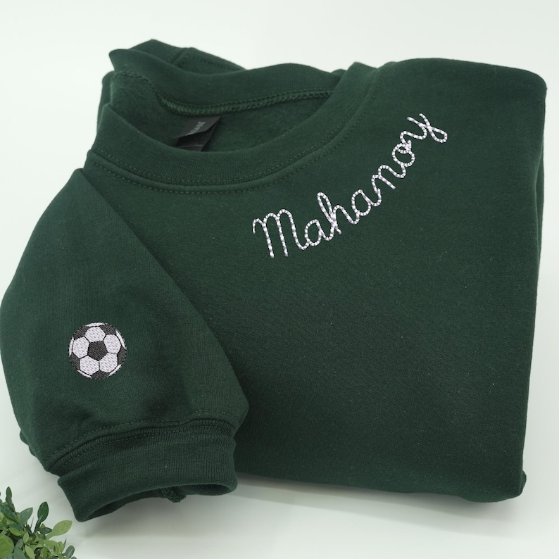Custom embroidered forest green sweatshirt with “Mahanoy” in white script and soccer ball sleeve design — personalized cozy spirit wear, perfect gift for soccer players, coaches, sports moms, or fans supporting their school and team during soccer season