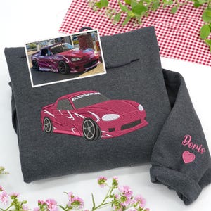 Dark heather embroidered sweatshirt with custom pink drift car embroidery and name “Doris” with heart on sleeve. Personalized car gift made from real car photo — perfect for car enthusiasts and racers.