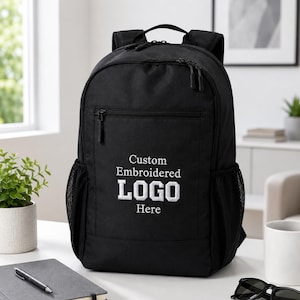 Könnte beinhalten: Ein schwarzer Rucksack mit einer vorderen Reißverschlusstasche und dem weiß gestickten Text Custom Embroidered LOGO Here. Der Rucksack verfügt über ein Hauptfach mit Doppelreißverschluss, einen Tragegriff, verstellbare Schultergurte und seitliche Netztaschen.