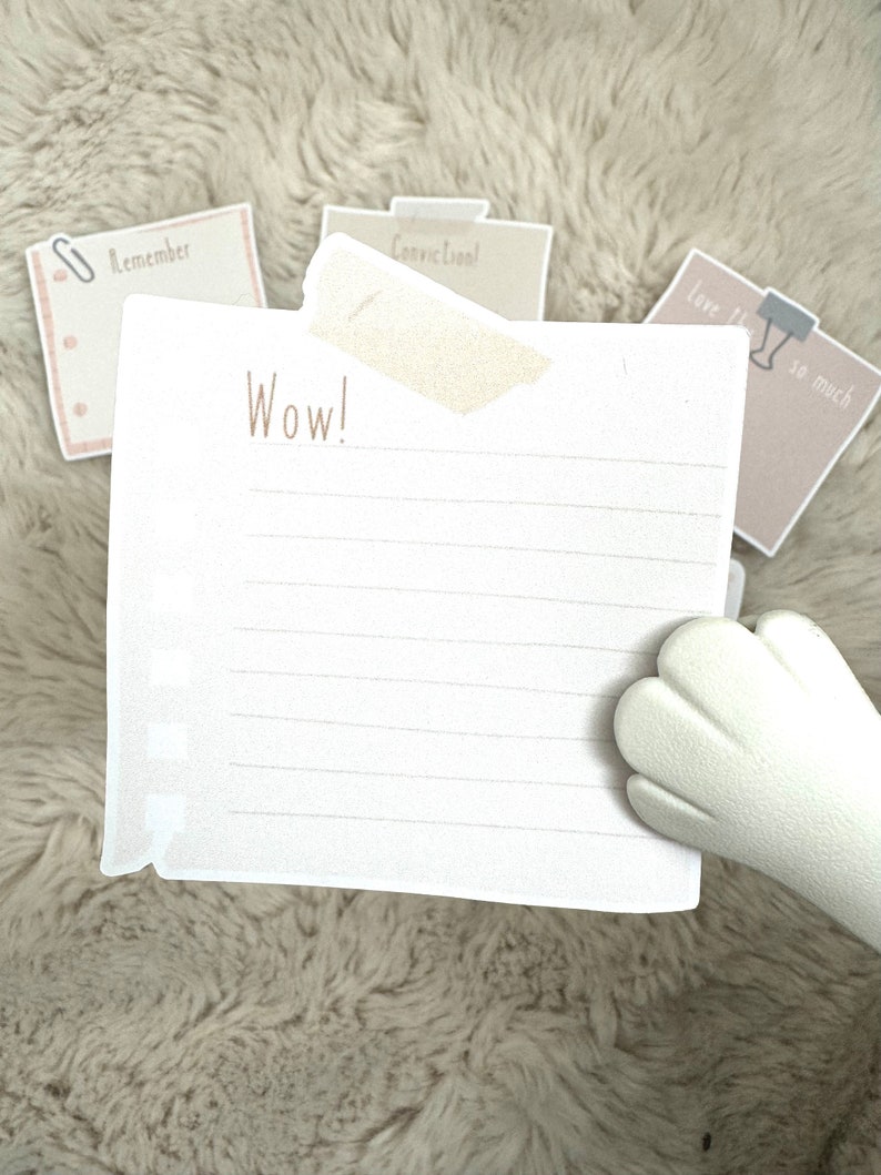 May include: A white lined notepad with the word "Wow!" written on it. The notepad is on a fuzzy white surface with three other notes visible in the background. The notes say "Remember", "Convic Cool!" and "Love this so much".