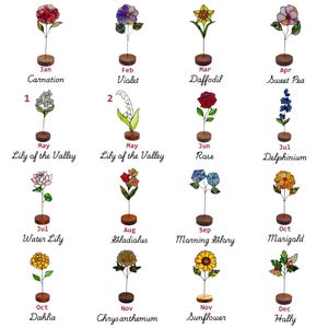 May include: A collection of sixteen stained glass flower ornaments, each mounted on a small circular wooden base. The flowers represent months of the year, labelled with names like Carnation, Violet, Daffodil, Rose, and Sunflower in black text.