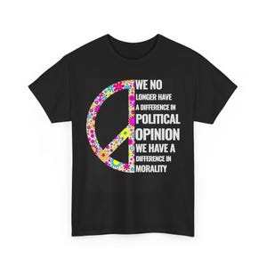 May include: Black t-shirt featuring a peace sign filled with colorful flowers. The shirt has the text "WE NO LONGER HAVE A DIFFERENCE IN POLITICAL OPINION WE HAVE A DIFFERENCE IN MORALITY" in white block letters.