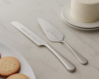 May include: A silver cake knife and server set with engraved text. The knife has the text "Owen and Charlotte" and the server has the text "The First Chapter".