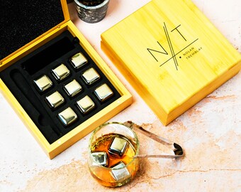 May include: A wooden box with a set of eight stainless steel whiskey stones, a pair of tongs, and a wooden stirrer. The box is engraved with the initials "N/T" and the name "Nolan Tremblay".