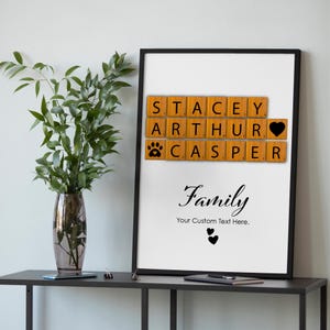 May include: A framed print with the word "Family" in elegant script. The names "Stacey", "Arthur", and "Casper" are spelled out with wooden letter tiles. A black heart and paw print are included.