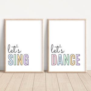 May include: Two framed prints with the text "let's sing" and "let's dance" in colorful letters on a white background.