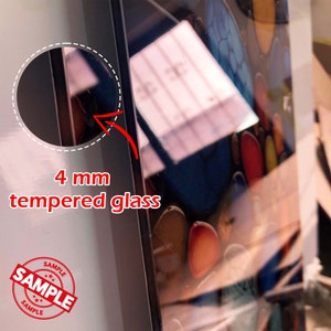 May include: Close-up of a 4 mm tempered glass panel. The glass is clear and reflects a colorful image of a sample product.
