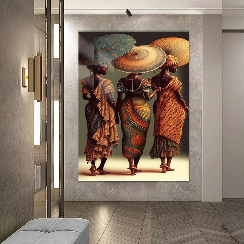 May include: Three women in colourful dresses and traditional headwear stand together, holding umbrellas. The women are facing away from the viewer, and their dresses are adorned with intricate patterns. The background is a muted green.