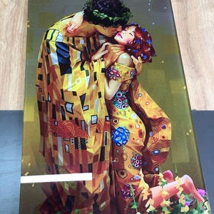 May include: A painting depicting a couple embracing in a colourful, abstract style. The man is wearing a yellow and brown patterned robe, and the woman is wearing a yellow and red patterned dress. The painting is set against a green background.