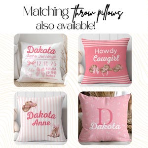 more options from the store! Four pink and white throw pillows with different designs. One pillow has a pink and white striped pattern with a brown cowboy hat and the text "Dakota Anne". Another pillow has a pink and white striped pattern with the text "Howdy Cowgirl". A third pillow has a white background with the text "Dakota Anne Jennings 12.10.25 4:21 AM 19 inches". The fourth pillow has a pink background with a white letter "D" and the text "Dakota".