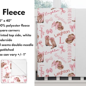 a personalized western themed baby girl blanket draped from a white crib. The name "Leighton" is all throughout the repeating pattern of cowgirl boots with pink bows and cowgirl hats with pink bows.