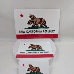May include: Three stickers with the New California Republic flag design. Each sticker features a brown bear with two heads, a red star, and the text "NEW CALIFORNIA REPUBLIC" in black on a white background with a red stripe.