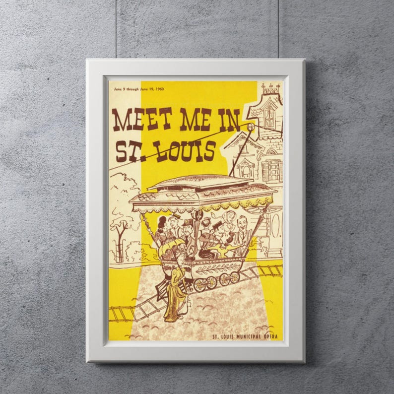 May include: A framed vintage poster with the text "Meet Me in St. Louis" in brown lettering on a yellow and cream background. The poster features an illustration of a trolley car with passengers and a building.