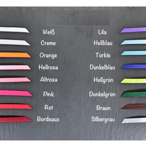 May include: A chart showing different colors of ribbon with the German names for each color. The colors are white, cream, orange, light pink, pink, red, burgundy, lilac, light blue, turquoise, dark blue, light green, dark green, brown, and silver gray.