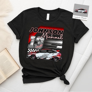 May include: Black t-shirt with a race car design. The shirt features the name "Johnson Michael" and the number "13". The car graphic is white, red, and black. A small image of the car is in the upper right corner.
